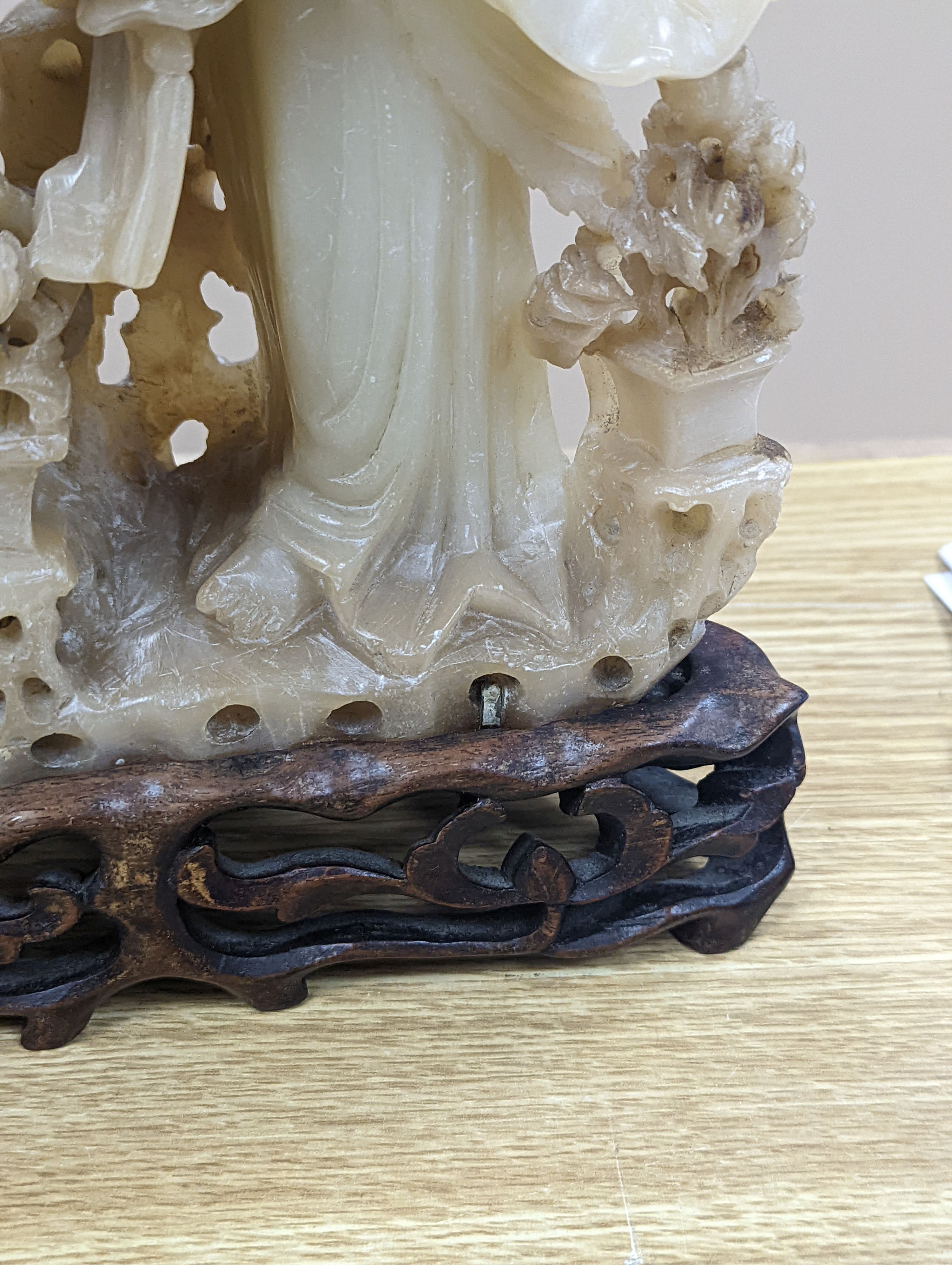 A Chinese soapstone carving of two ladies, wood stand, early 20th century, 36 cms high.